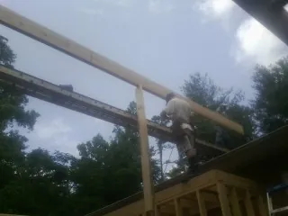 Carpenter setting a ridge beam over a new addition frame — Ice Dam Removal by Roofing Brothers in Spring Branch