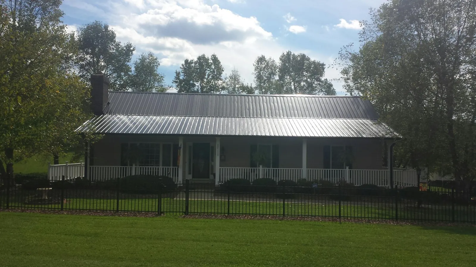 Gray metal roof on a brick ranch with a full width front porch — Gutter Guard Installation work by our crew in Spring Branch